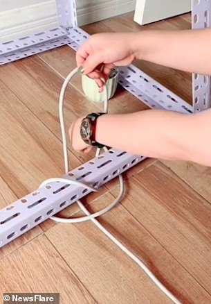 She feeds a few inches of cord through to the far side and uses the wire to create a figure-eight knot