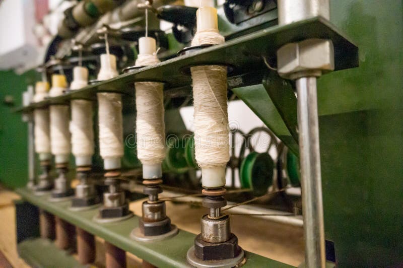 Green spindle weaving machine used to make cloth. The multiple spools of thread and the mechanized system helps make the cloth making process easier and stock images