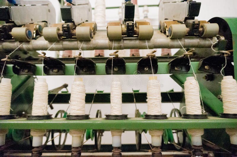 Green spindle weaving machine used to make cloth. The multiple spools of thread and the mechanized system helps make the cloth making process easier and roya