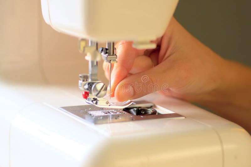 Preparing the sewing machine for work. Close up view. Preparing the sewing machine for work. Seamstress tucks thread into the eye of a needle. Installs the royalty free stock photos